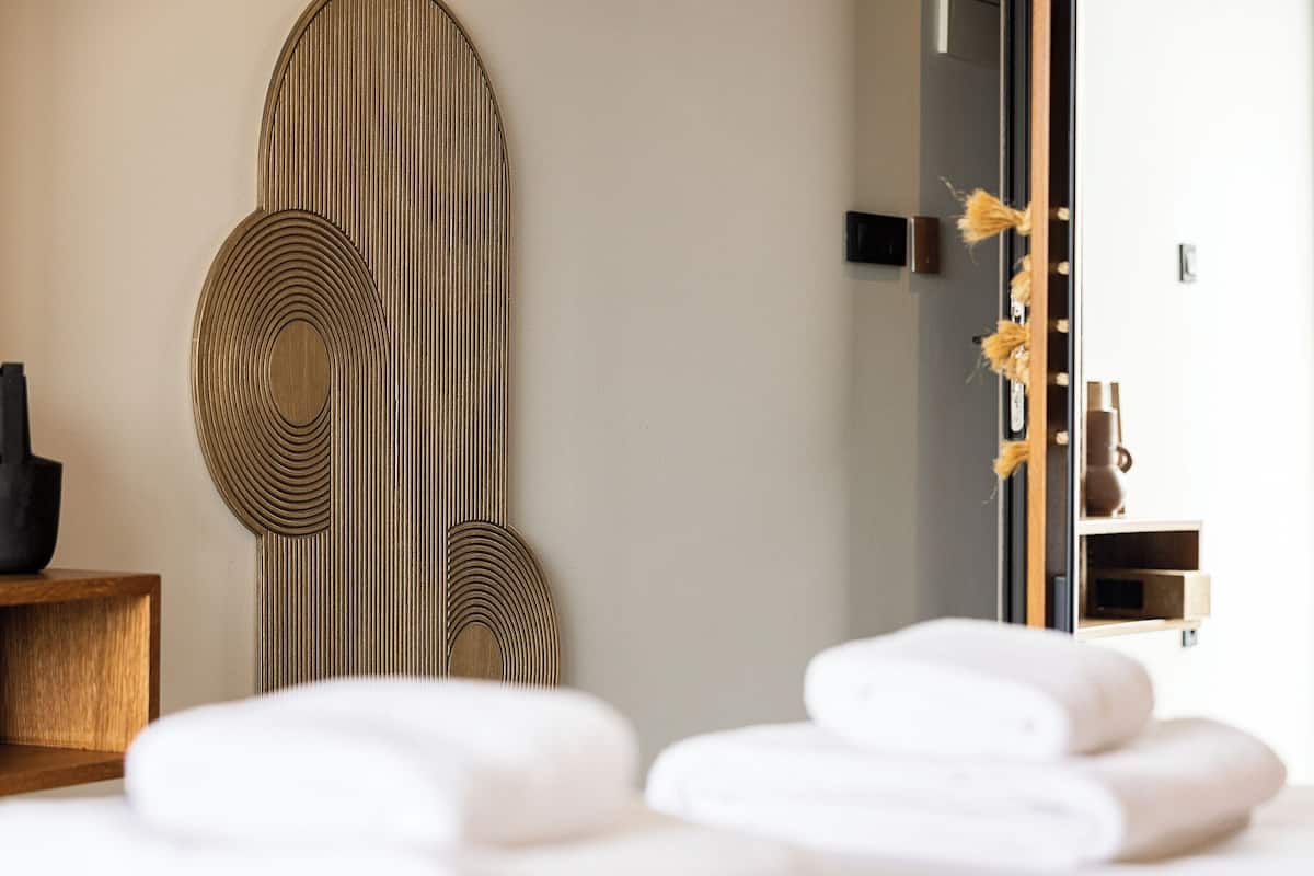 Ein modernes Zimmer mit einem großen Spiegel, Holzbildern an der Wand und einem Holztischchen.