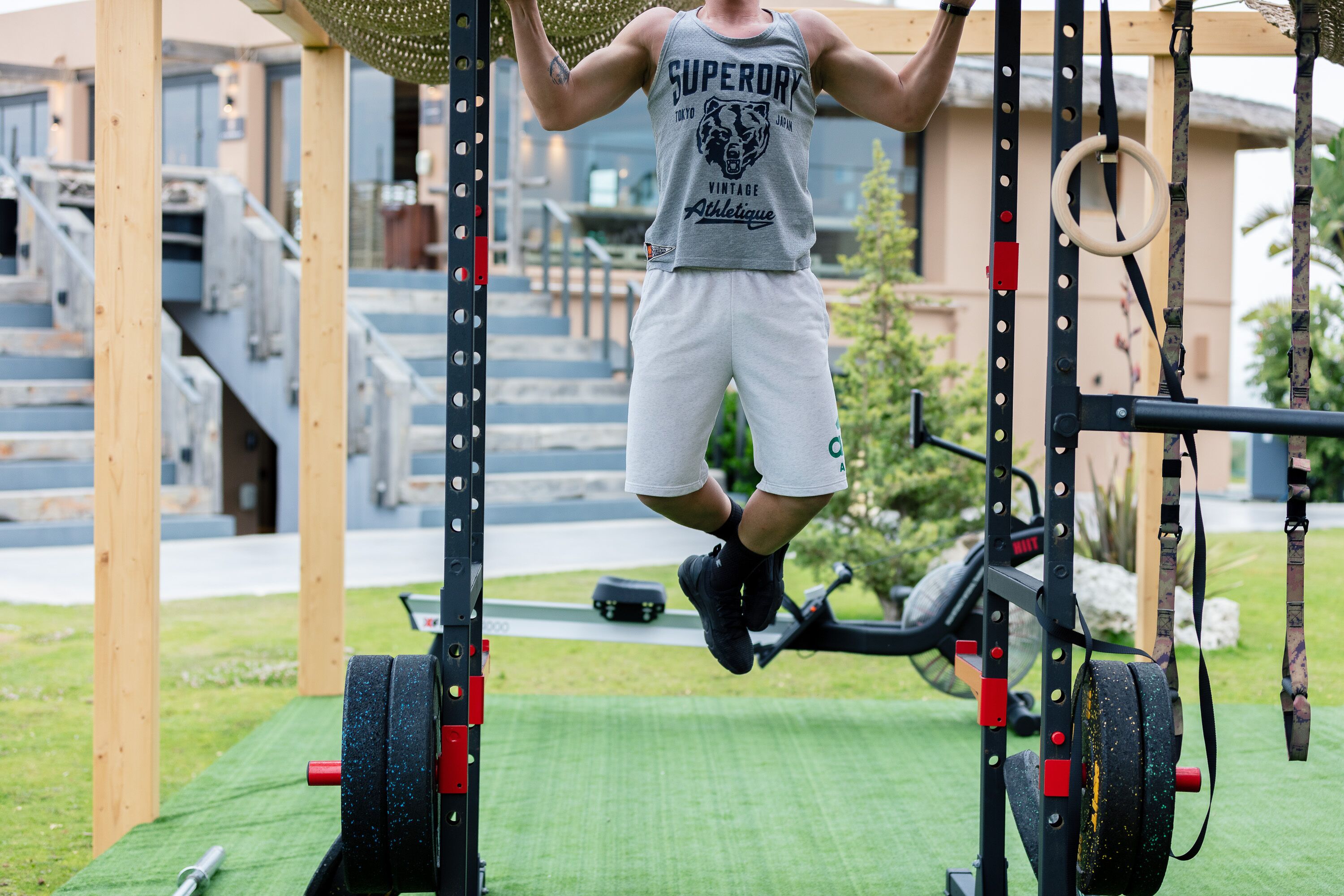 A person performing pull-ups on a gym apparatus outdoors.