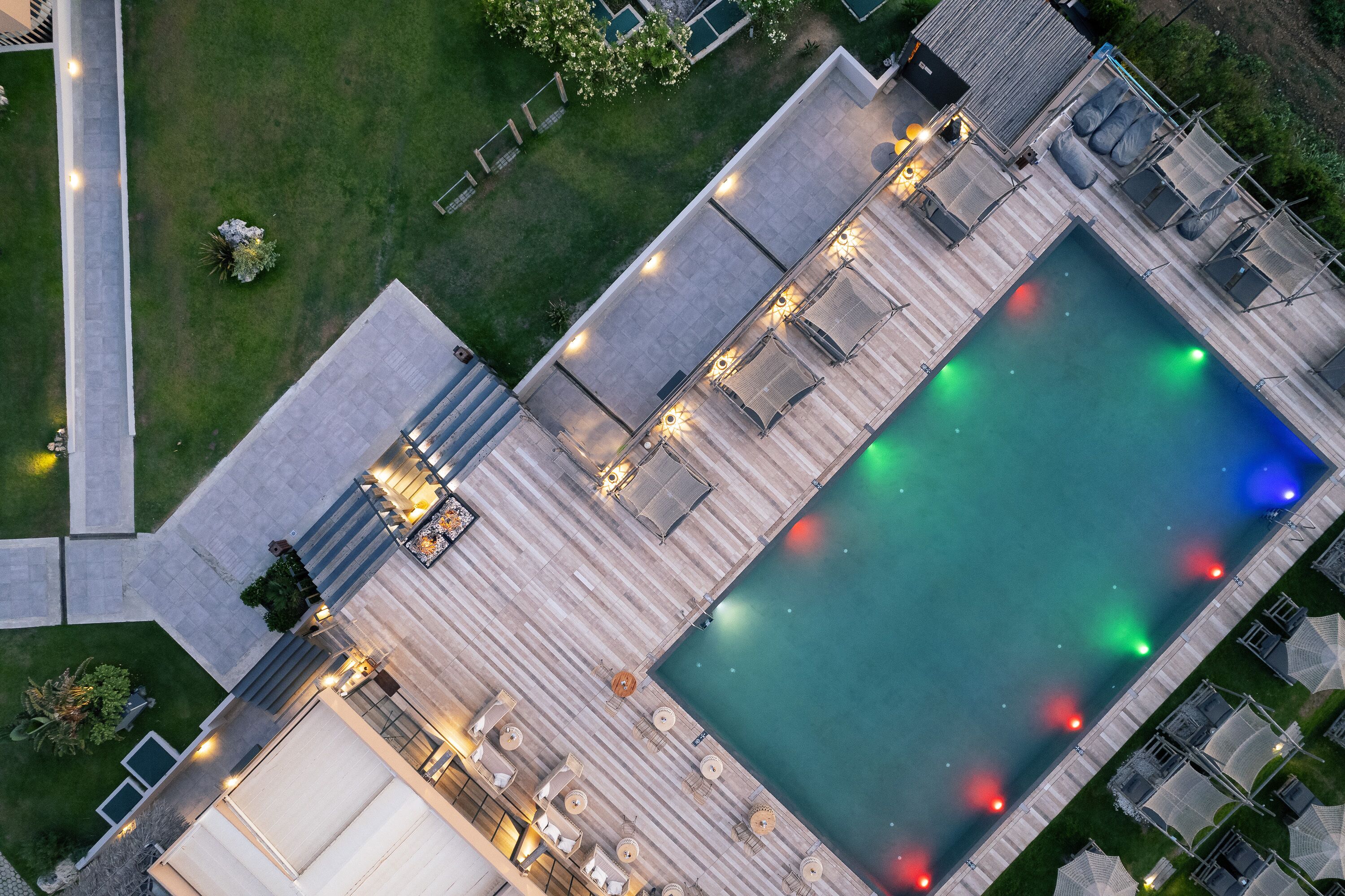 An aerial view of a swimming pool area with a deck, lounge chairs, and a covered seating area.