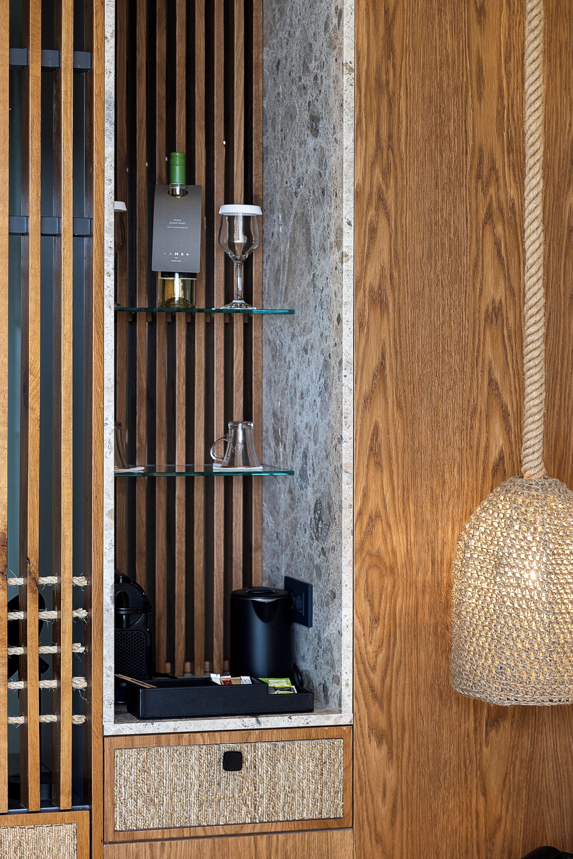A modern kitchen with wooden cabinetry, a built-in wine rack, and a hanging light fixture.