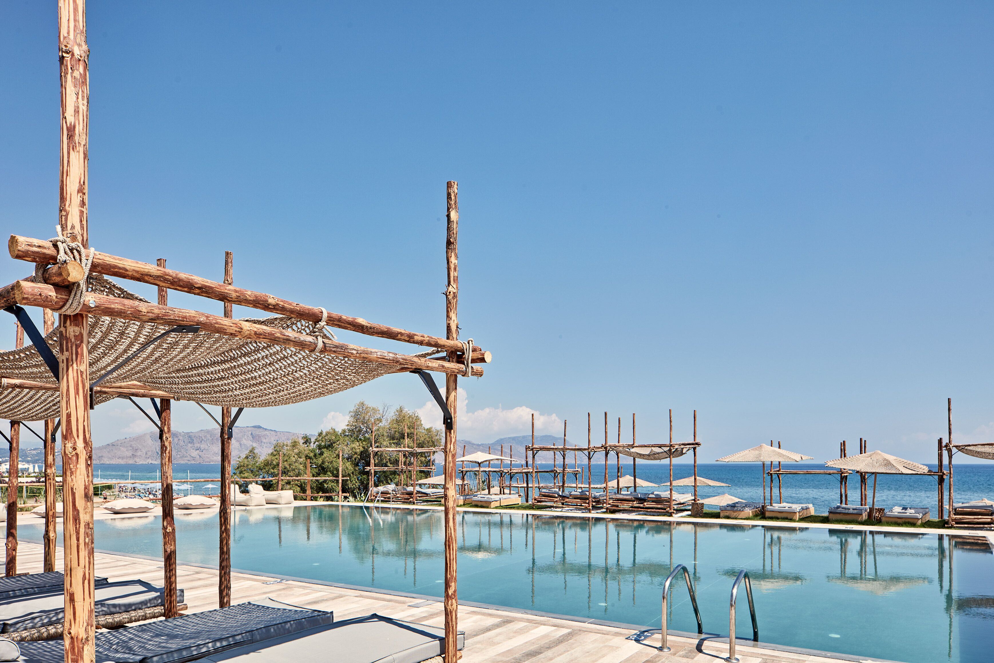 Un espace aménagé au bord de la piscine, avec des pergolas en bois et des chaises longues.