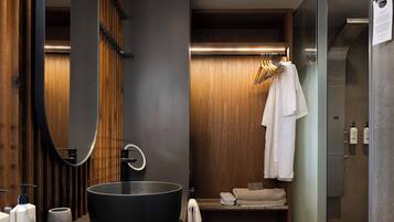 Une salle de bain moderne avec un grand lavabo noir, un lambris en bois, un miroir et un porte-serviettes.