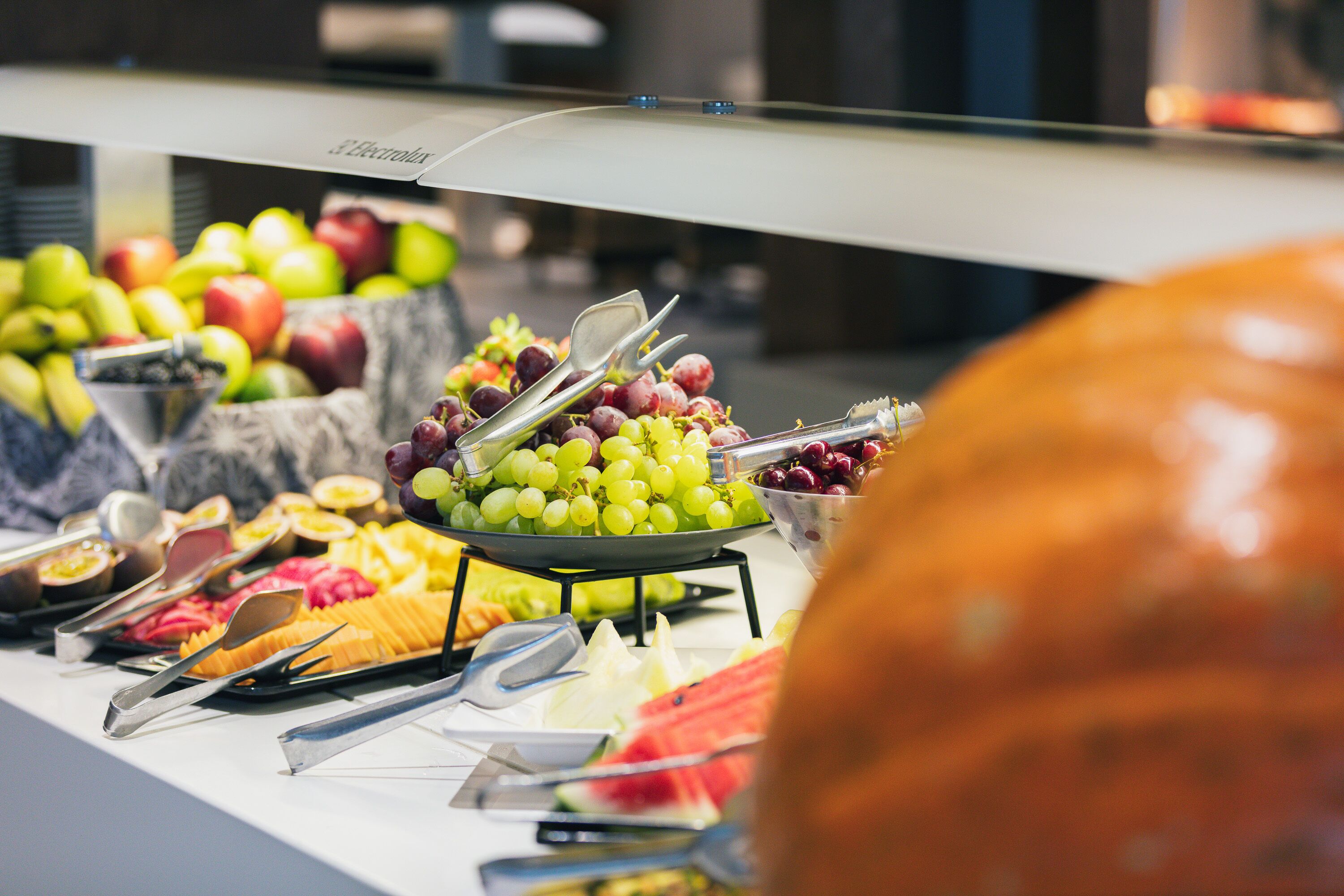 A buffet with various fruits and vegetables, including apples, grapes, and carrots.