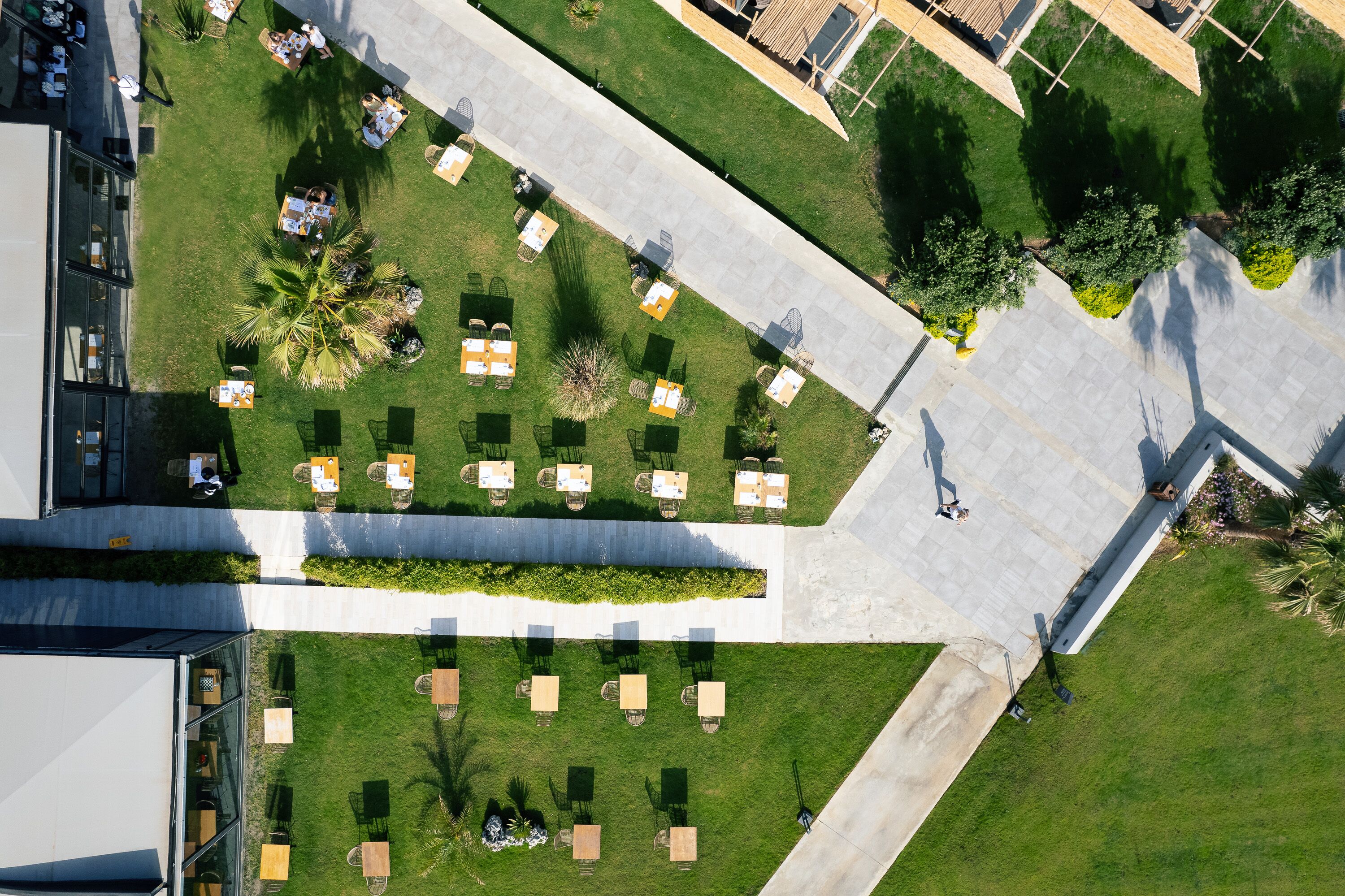 Vista aérea de un patio con mobiliario exterior, una fuente central y abundante vegetación.