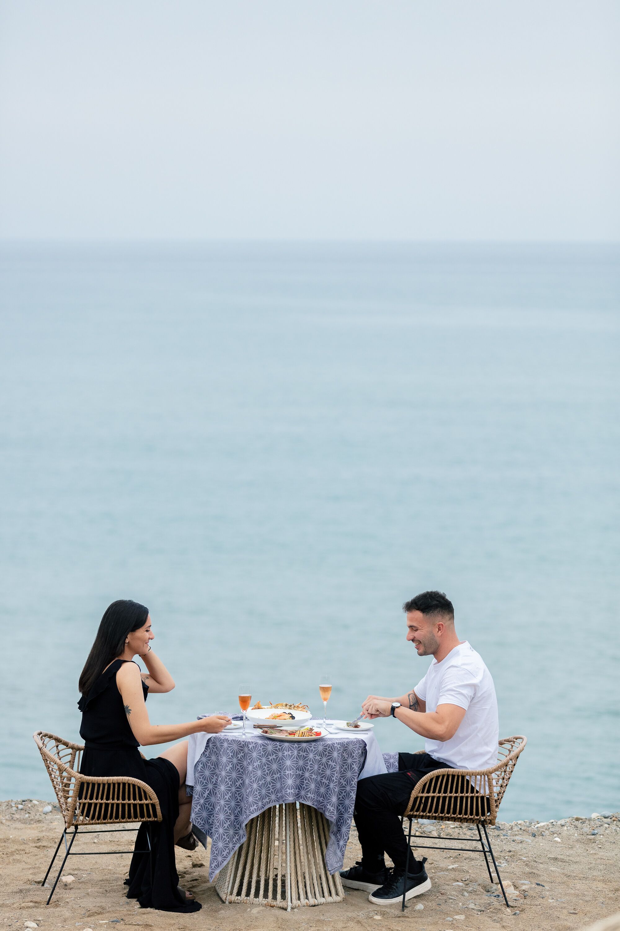 Deux personnes sont attablées et dînent, avec une vue sur la mer.