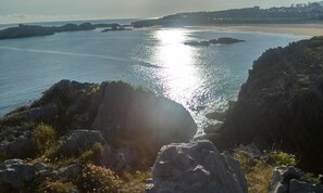 A coastal landscape with rocky outcrops and a calm sea. - Hostal Isla Playa (Arnuero)