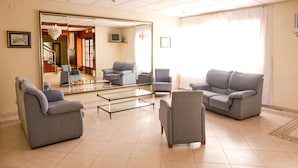 A spacious living room with a large mirror reflecting the interior, a grey sofa set, and a coffee table. - Hostal Isla Playa (Arnuero)