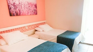 A hotel room with two beds, a pink wall, and a window. - Hostal Isla Playa (Arnuero)