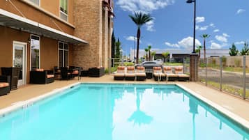 Una piscina al aire libre, sillones reclinables de piscina