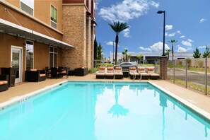 A pool area with lounge chairs and a building with a stone facade.