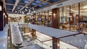 A modern hotel atrium with a glass ceiling, multiple floors, and a central staircase. - DoubleTree by Hilton Skopje (Skopje)