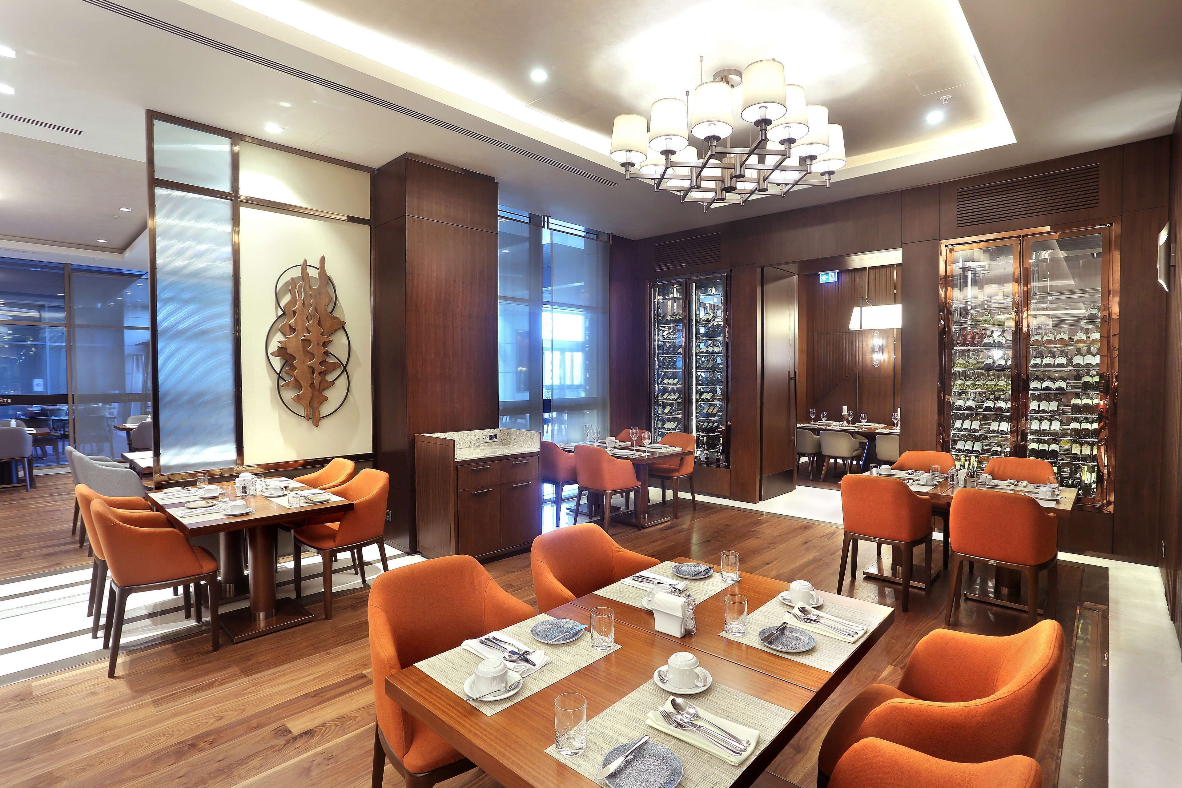 Un restaurant modern amb terres de fusta, cadires taronja i taules de dinar ben preparades.