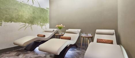 A spa room with three reclining chairs, a wall mural, and a herringbone-patterned floor.