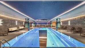 A modern indoor pool with a starry ceiling, lounge chairs, and a central seating area. - DoubleTree by Hilton Skopje (Skopje)