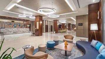 En modern hotellobby med en receptionsdisk, sittgrupper och en skylt som visar vägen till Monte Restaurant.