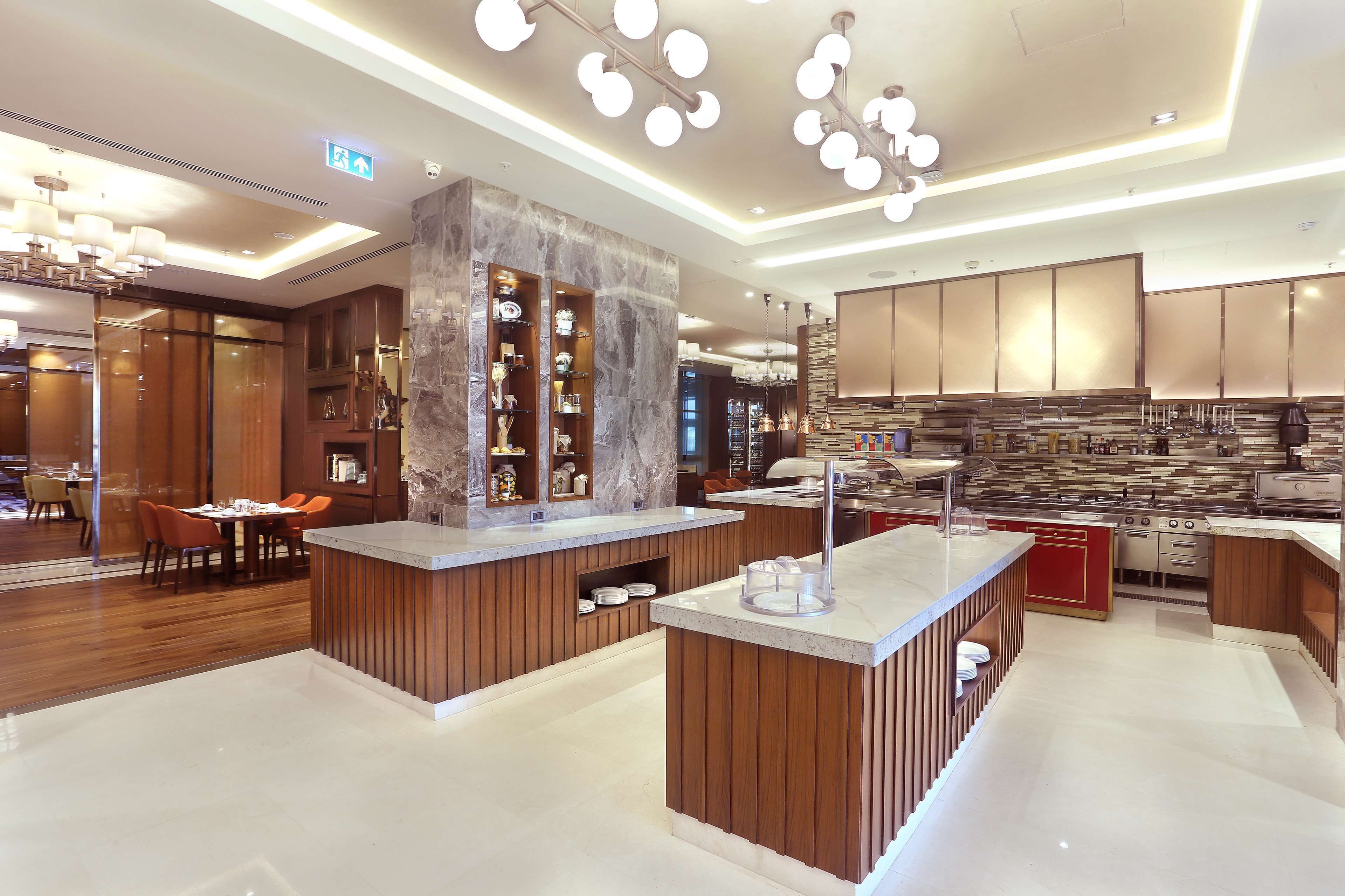A modern kitchen with wooden cabinets, marble countertops, and a central island.