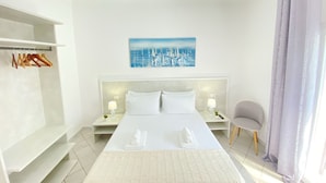 A hotel room with a bed, two bedside tables, a chair, a wardrobe, and a painting on the wall. - B&B Fellini (Gallipoli)