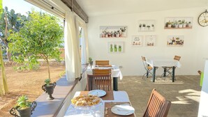 An outdoor dining area with tables set for a meal, surrounded by potted plants and framed pictures on the walls. - B&B Fellini (Gallipoli)