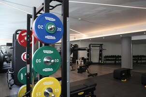 Et fitnesscenter med styrketræningsudstyr, bænke og håndvægte.