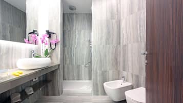 Une salle de bain moderne avec un grand miroir, un lavabo blanc, un bidet et une baignoire.