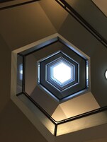 Et geometrisk loftsdesign med en central lysekrone.