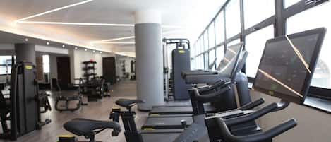 A gym with cardio equipment, weight machines, and large windows.