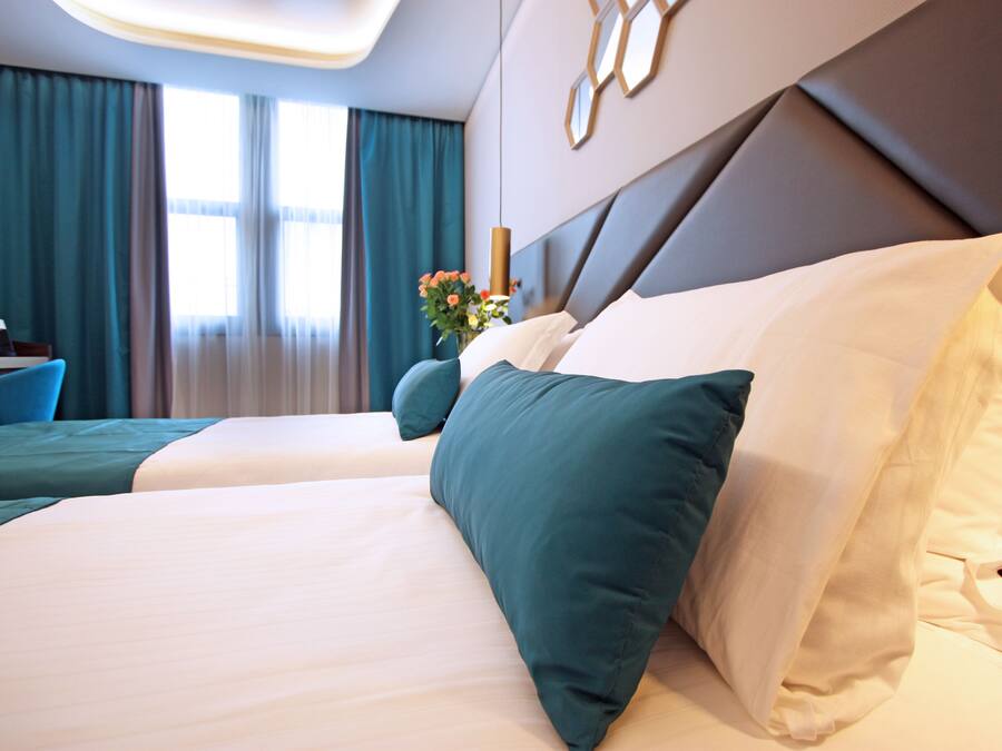 Ein Hotelzimmer mit zwei Betten, einem Schreibtisch und Blick auf die Stadt.