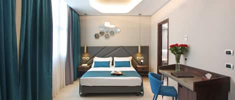 A modern hotel room with a large bed, a desk with a chair, and a decorative wall piece.