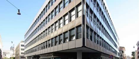 Un edificio moderno con fachada plana, múltiples ventanales y un área de acceso cubierta.