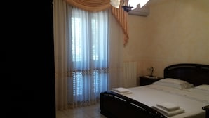 Un dormitorio con cama, mesita de noche, lámpara y ventana con cortinas.