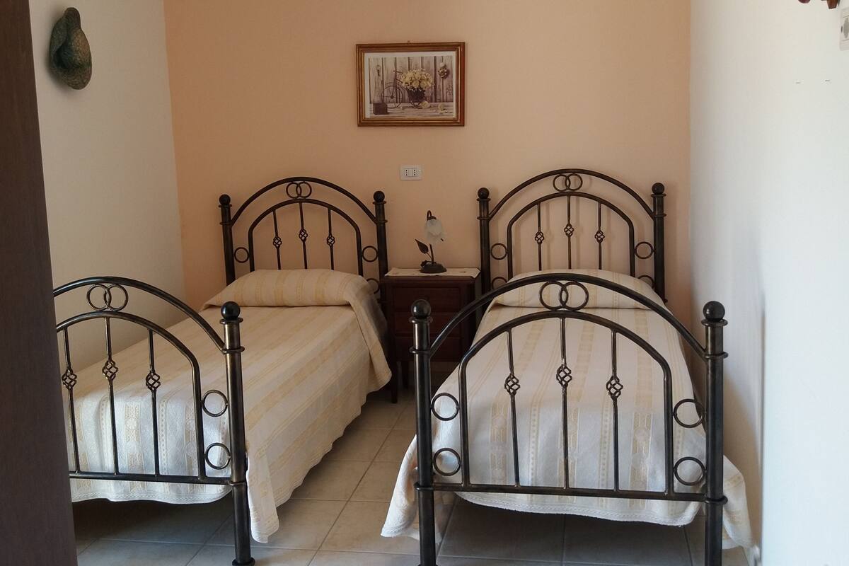 Un dormitorio con dos camas, una mesita de noche, aire acondicionado instalado en la pared y un cuadro enmarcado.