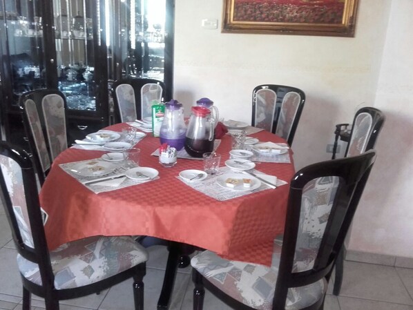 Una mesa de comedor dispuesta con platos, vasos y salsas.