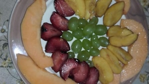 Un plato con una variedad de frutas, como melón, uvas y melocotones.