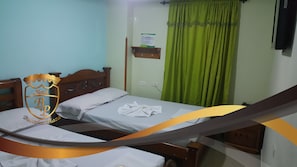 Habitación de hotel con dos camas, cabecera de madera, cortina verde y estante fijado a la pared.