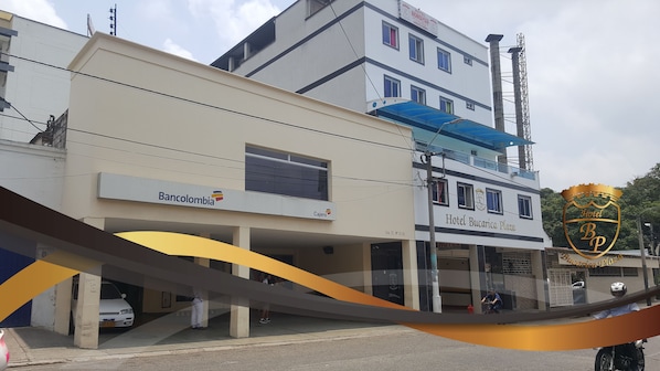 Un edificio con un letrero que indica 'Hotel Bucarica Plaza' y 'Bancolombia' en la fachada.