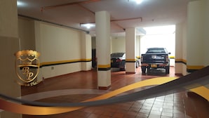 Eine Tiefgarage mit weißen Säulen und gelben Markierungen, ein schwarzer SUV und das Logo des Hotel BP Buciari Plaza.