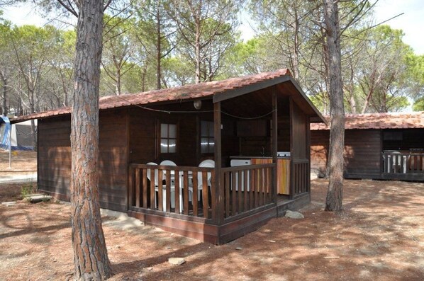 A rustic cabin with a wooden porch, surrounded by trees.