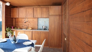 A wooden kitchen with a sink, stove, and cabinets. There is a table with a blue tablecloth and chairs.
