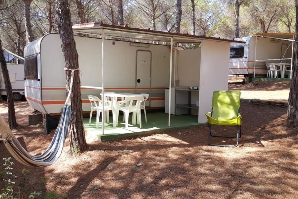 A campsite with a covered dining area, a table with chairs, and a hammock.