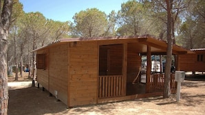 A wooden cabin with a porch, surrounded by trees.