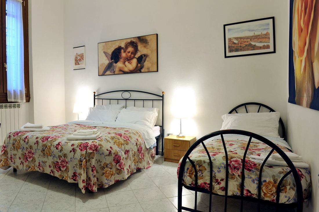 A bedroom with two beds, a nightstand, and a wall with framed pictures.