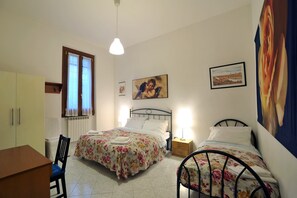 Un dormitorio con dos camas, un escritorio, una silla, un armario y una ventana con cortinas.
