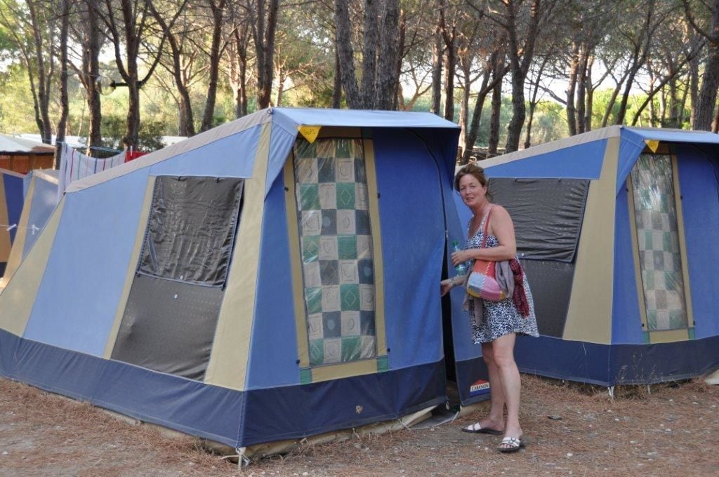 Un terrain de camping avec plusieurs tentes, dont l’une a une porte à motifs à carreaux.