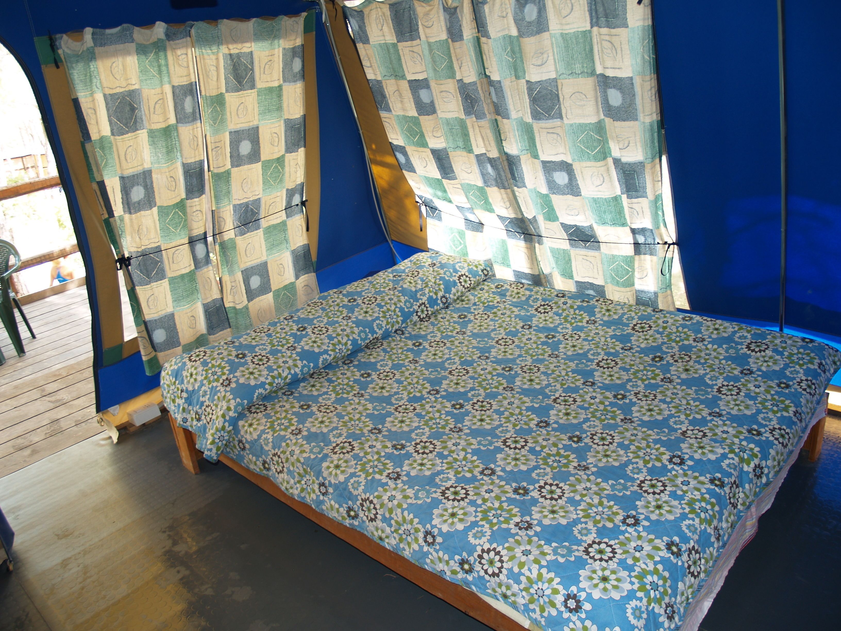 A room with a bed, curtains, and a view of the outside.