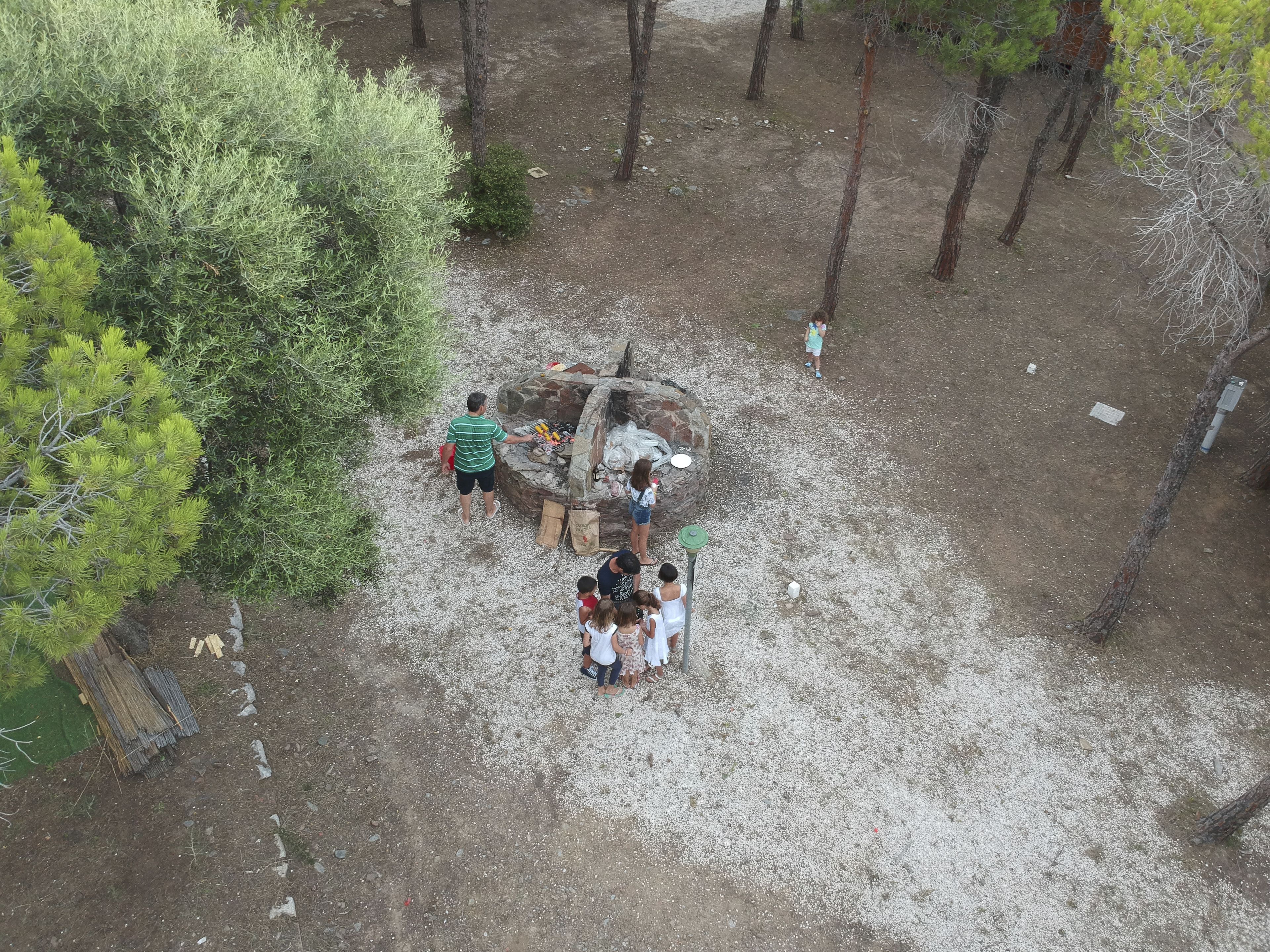 An aerial view of a campsite with a fire pit surrounded by people.