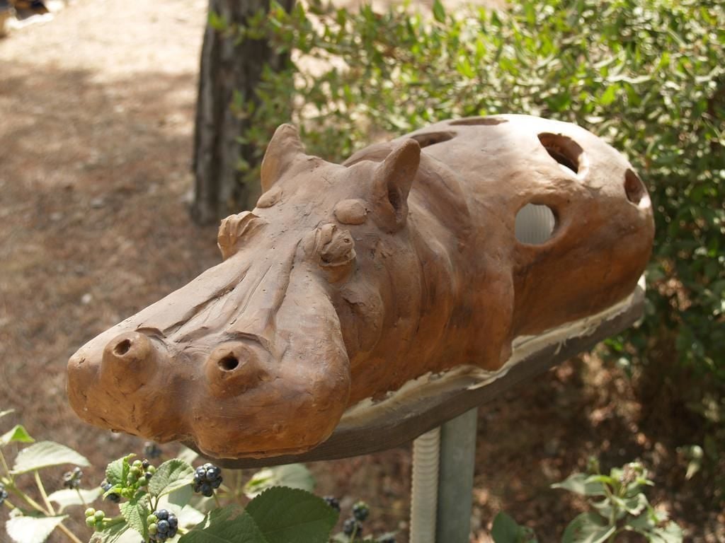 A clay sculpture of a hippo's head on a display stand.