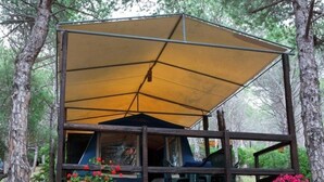 Una cabaña de madera con un toldo amarillo, rodeada de árboles.