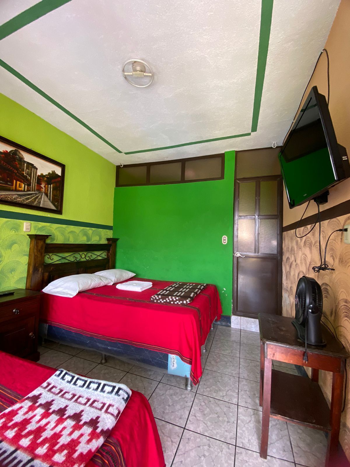 A room with two beds, a television, and a fan.