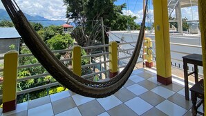 Una hamaca sobre un suelo de baldosas con vista a una montaña y un edificio al fondo.