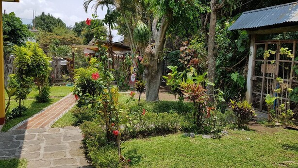 Un jardín con un sendero de piedra que lleva a un edificio con techo de metal corrugado.
